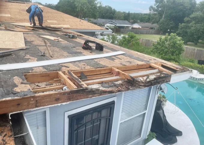 Expert Affordable Roofing technician repairing rotted fascia and decking near a pool enclosure